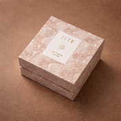 Square cardboard box with decorative patterns and a label on a brown background. Zeyn OudAmbraBox_Refill_PDP_Elevated
