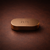 ZEYN Tabac Arabe solid perfume balm in bronze metal device resting on dark leather surface